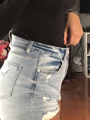 reviewer shows denim shorts too big on waist before using extra jean button