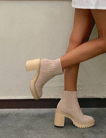 Person in a white dress showcasing beige ankle boots with chunky heels