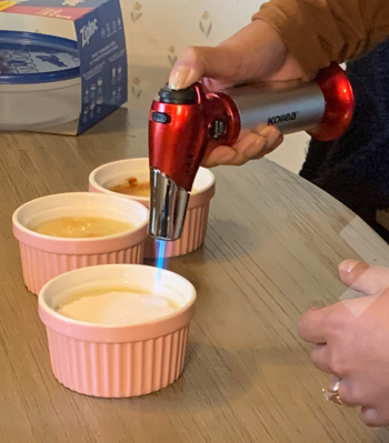 Reviewer using small blow torch on creme brulees 