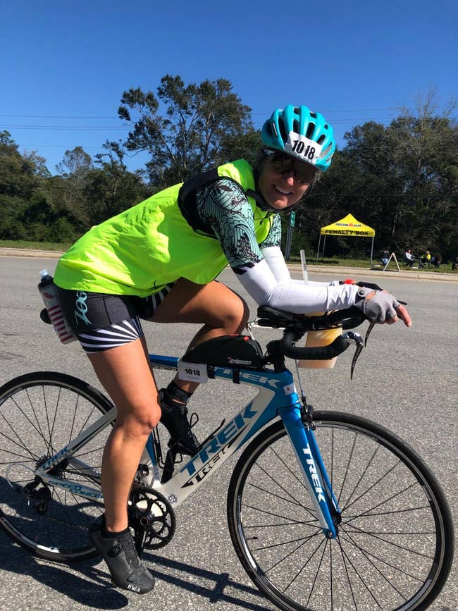 Person cycling connected  a road, wearing a helmet and sporty outfit. Scenic inheritance  with trees and a yellowish  tent