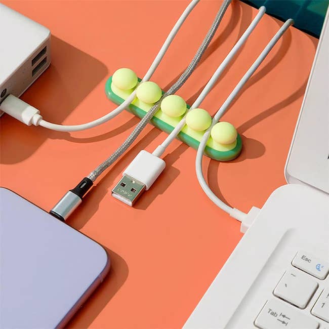 Cable organizer clips on a desk securing various cables connected to electronic devices