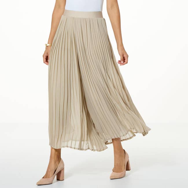 Person wearing a pleated maxi skirt and block heel shoes, showing a stylish, flowing look ideal for casual or formal occasions