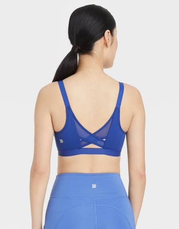 back of model wearing the blue bra, showing the mesh panels and criss-cross design