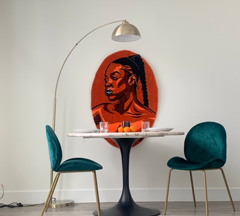 a reviewer photo of the lamp over a small dining table with two green chairs