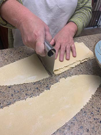 reviewer using the bench scraper to cut sheets of pasta dough