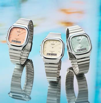 three watches with varying pastel colors of ticker faces, including pink, yellow, and green
