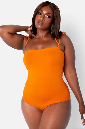 a model posing in an orange bodysuit