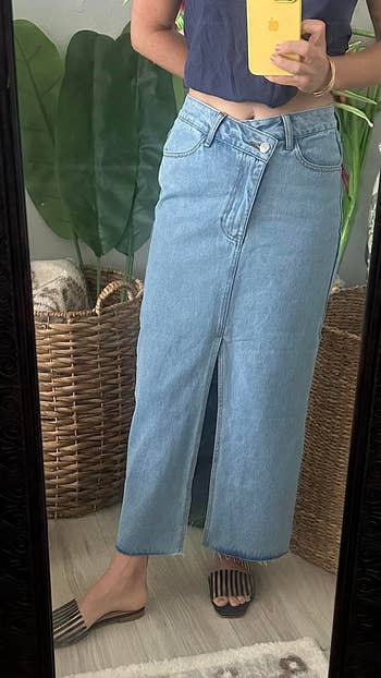 Person modeling a high-waisted, ankle-length denim skirt with a beforehand   slit, paired with slip-on sandals successful  a buying  nonfiction  context