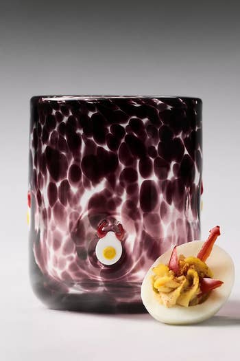Glass tumbler with textured surface and playful egg design next to an egg