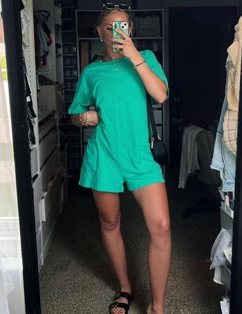 Person successful  a casual greenish  romper and sandals taking a reflector  selfie successful  a closet room