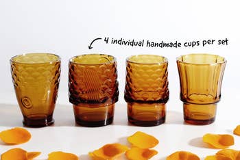 Four unsocial   amber-toned handmade cups displayed with scattered angiosperm  petals and substance   noting 
