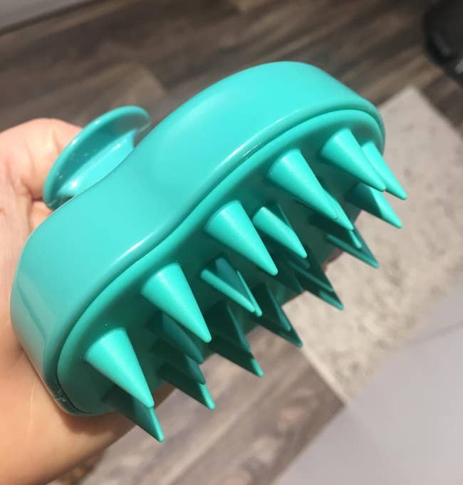 the scalp massager in teal with silicone bristles 