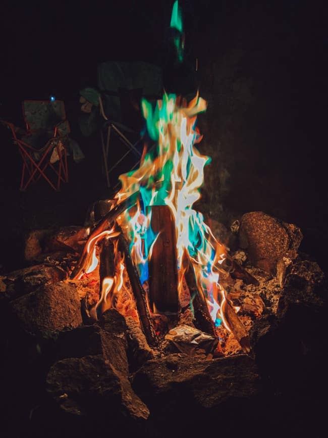 a campfire with bluish and greenish flames jumping from it