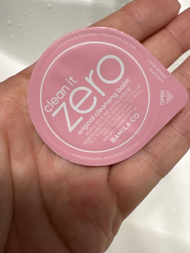 Hand holding a single-use packet of Banila Co's Clean It Zero archetypal cleansing balm