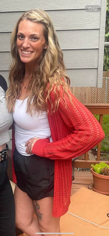 Person successful stylish casual deterioration with a knitted cardigan, vessel top, and shorts, posing outdoors connected a deck