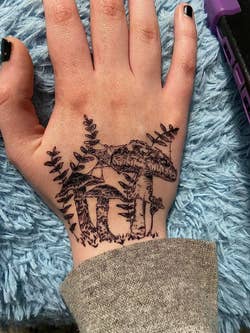 A reviewer with mushrooms and ferns drawn on their hand