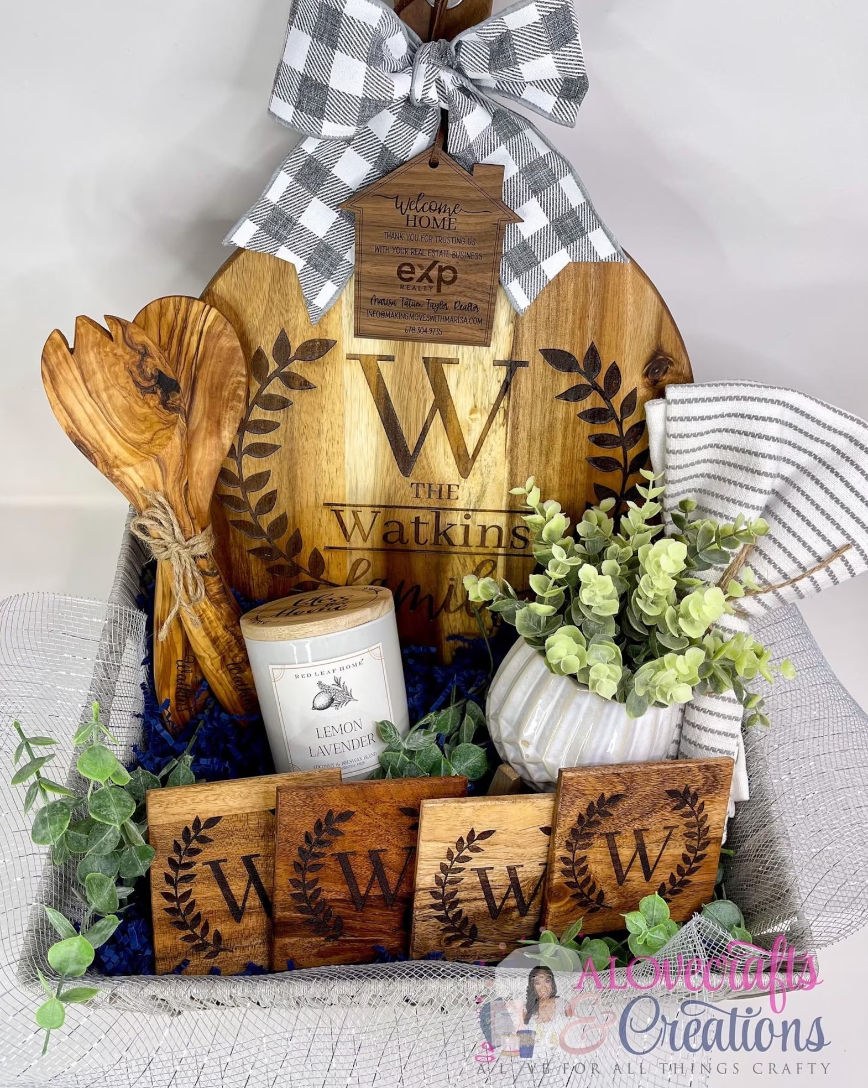 Gray basket filled with engraved wooden coaster, wooden cooking utensils, a wooden engraved cutting board, a lemon lavender candle, a succulent, and a white and gray dishcloth 
