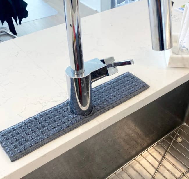 a navy faucet splash catcher around a kitchen faucet