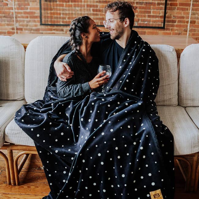 couple on couch wrapped in big polka-dotted blanket