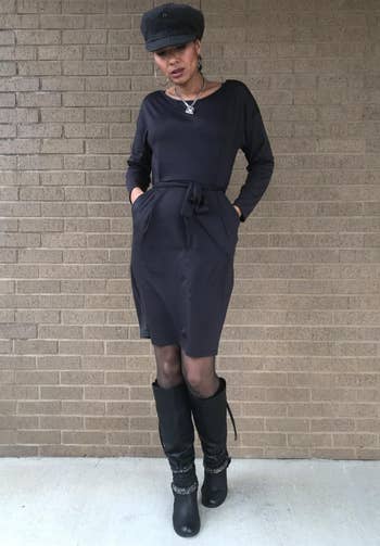 reviewer wearing the black dress with tights and black boots