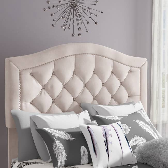 A cream headboard with an arch and upholstery 