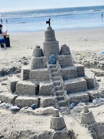 Detailed sandcastle connected  a beach, featuring tiers, tiny   staircases, and a tiny  emblem  connected  top