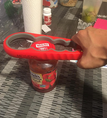 Reviewer using red multigrip tool to encase a jar lid and pull it open