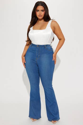 A idiosyncratic   models a fitted achromatic  apical  and high-waisted flared bluish  jeans, lasting  confidently