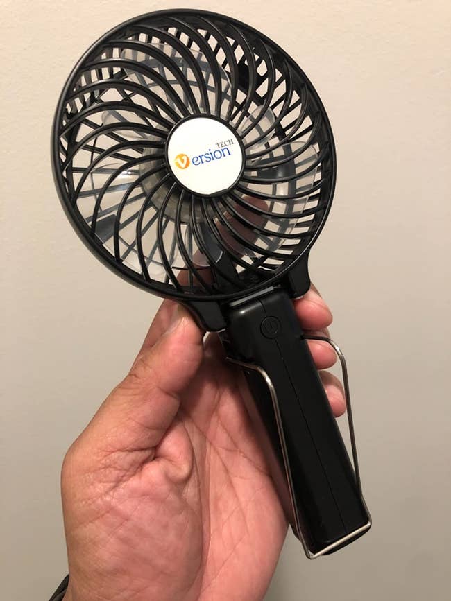 reviewer holding the small portable fan in black