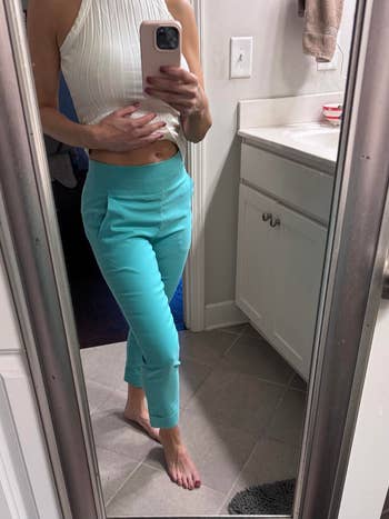 Person taking a reflector  selfie wearing a sleeveless apical  and fitted pants, showcasing a casual outfit