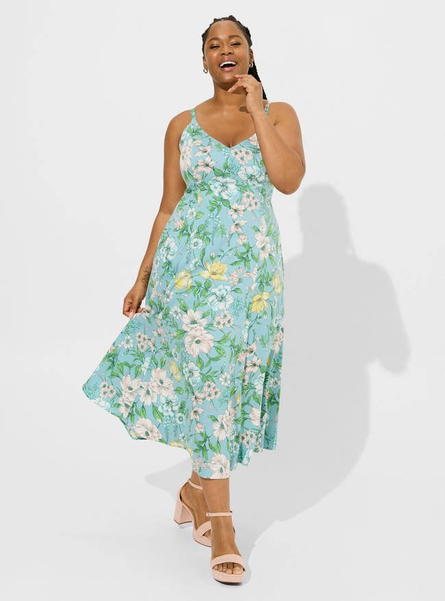 Model in a blue and green floral sleeveless midi dress and beige heels 