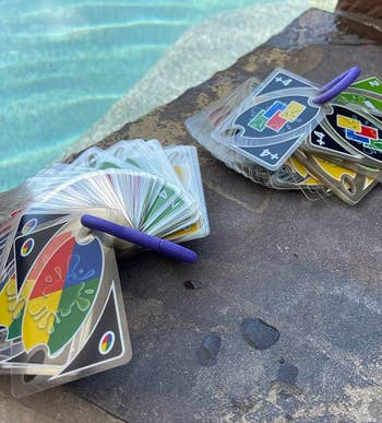 A reviewer's deck of Uno cards is scattered near a pool's edge