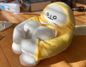 reviewer photo of the stuffed doll curled up and holding its legs