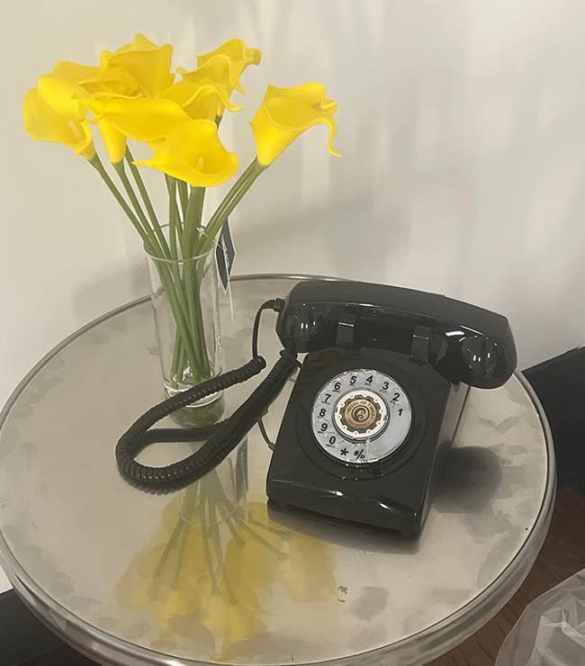Black rotary phone sitting on an end table 