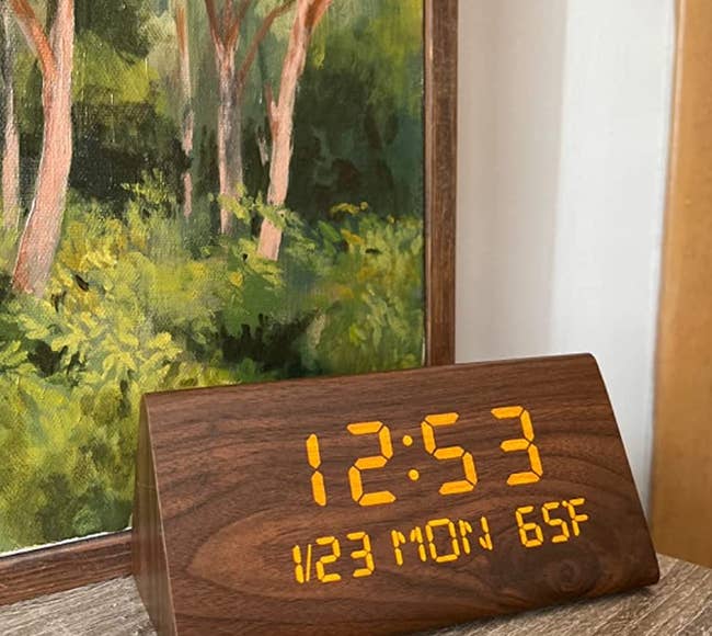 a reviewer shows a close up of their wooden clock on a side table