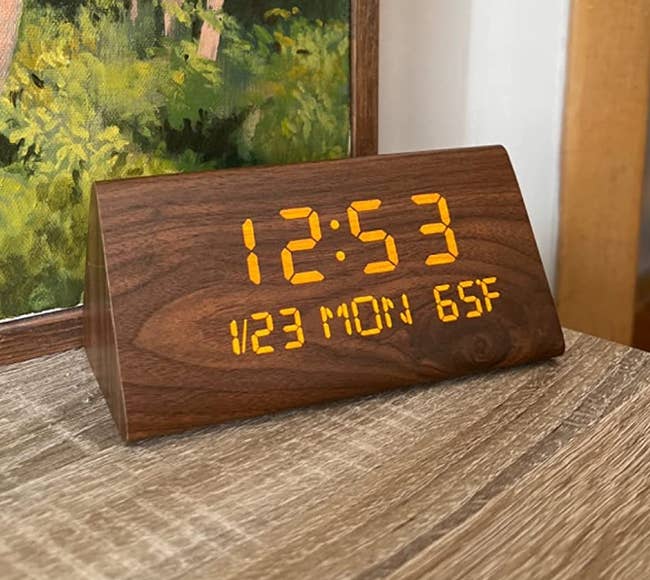 a reviewer shows a close up of their wooden clock on a side table