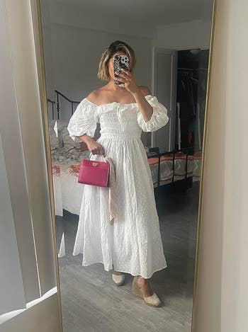 reviewer in mirror taking selfie, wearing white puff-sleeved dress and holding pink handbag