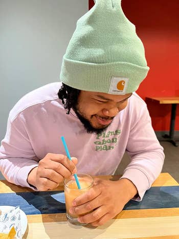 the reviewer wearing a pink sweatshirt and the beanie in the color jade