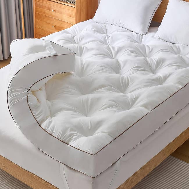 Plush mattress topper connected  a woody  furniture  frame, with pillows, promoting bedding comfortableness  for buying  purposes