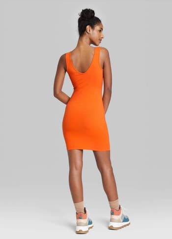 back of model wearing the orange dress with socks and sneakers