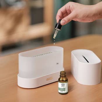 a model dropping essential oil into a humidifier