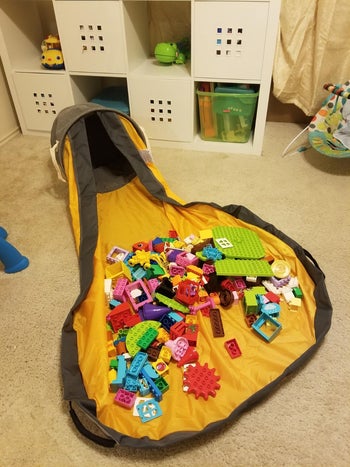 the bag lying on its side with the mat open and toys on it