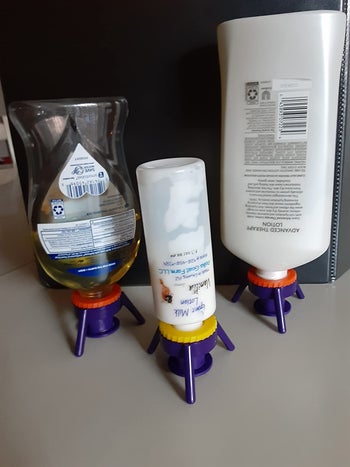 reviewer image of three bottles flipped upside down with the purple flip top keeping them stable