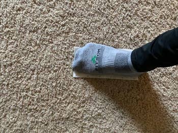 reviewer stepping on stomp n' go stain removal pad on carpet