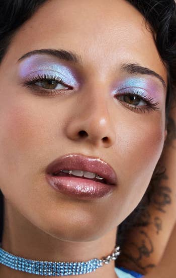 Close-up of a idiosyncratic with glossy lips, metallic eyeshadow, and a beaded choker, showcasing a bold quality look