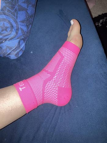 Foot wearing a pink, patterned compression sock connected a bluish couch, highlighting comfortableness and enactment for buying article