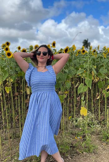 reviewer posing in front of a sunflower field wearing the dress