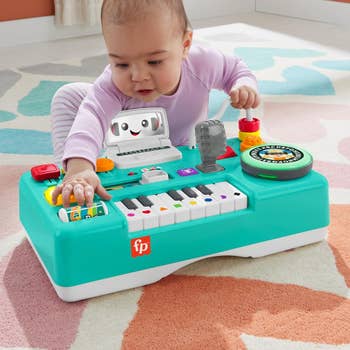 a baby playing with the dj turntable set without the legs on it