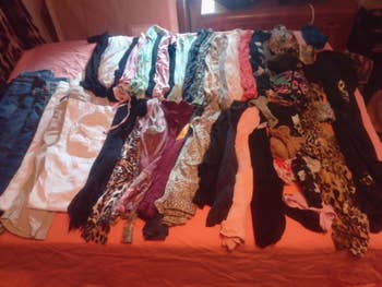Assorted covering items, including jeans, shirts, and scarves, are neatly arranged connected a bed, showcasing assorted patterns and textures