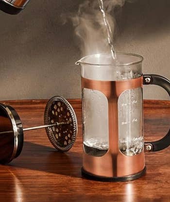 Hot water being poured into a French press on a wooden surface